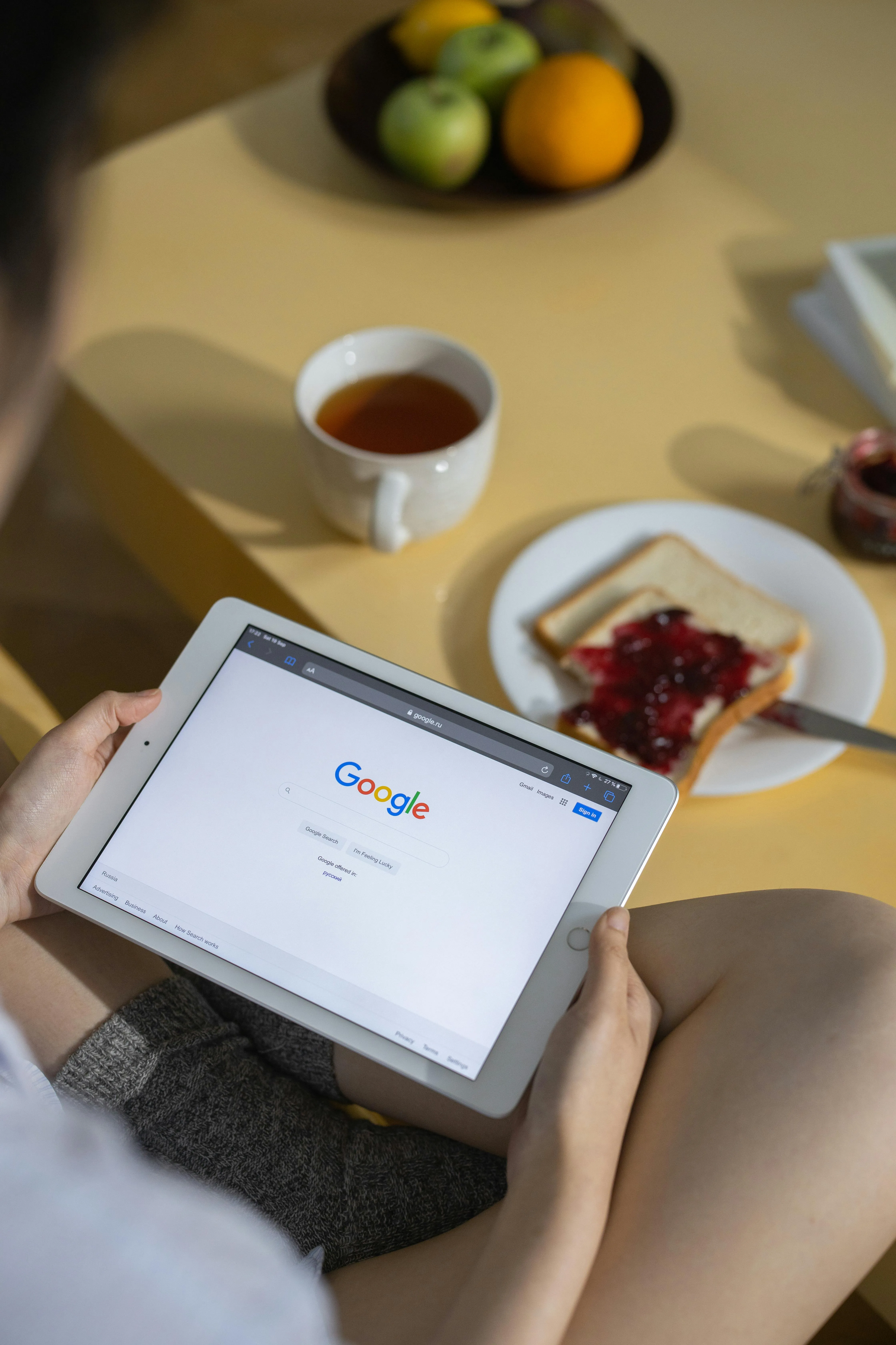 Man holding an iPad displaying the Google search engine homepage on the screen.