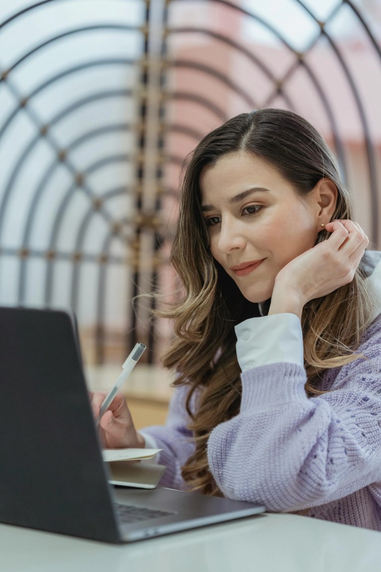 A smiling woman using a laptop and browsing an educational website with a clear, well-aligned layout.