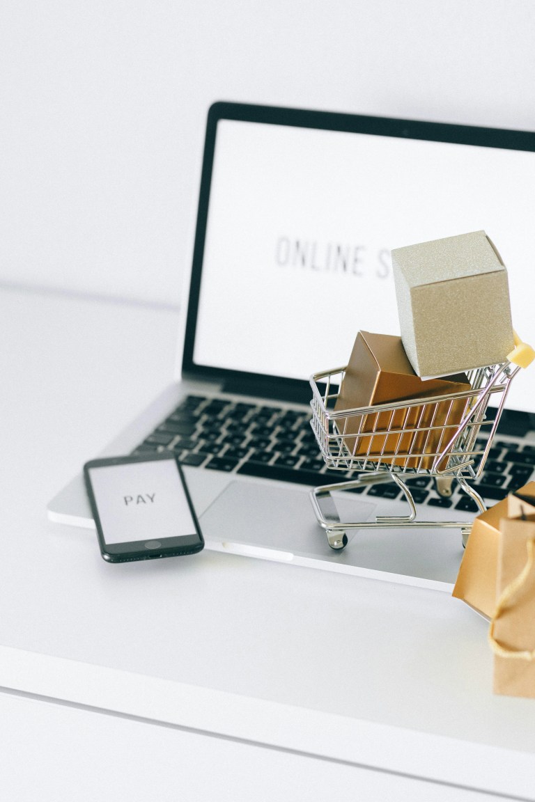 Ecommerce concept with shopping cart, laptop, and phone representing online payments and digital shopping